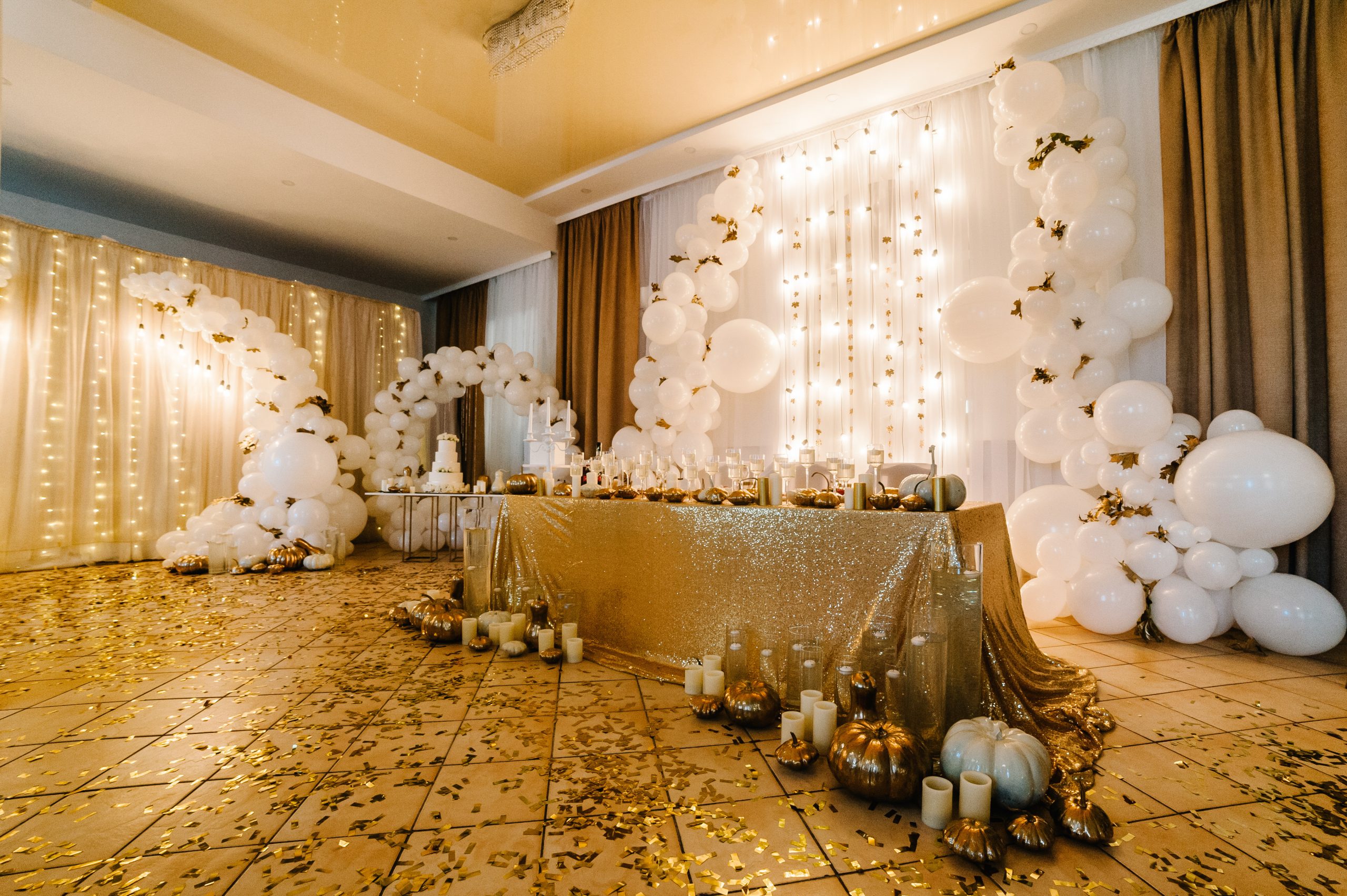 Table setting for wedding. Decorated arch for wedding ceremony. White balloons, candles, autumn leaves and small pumpkins. Autumn location and Halloween decor.